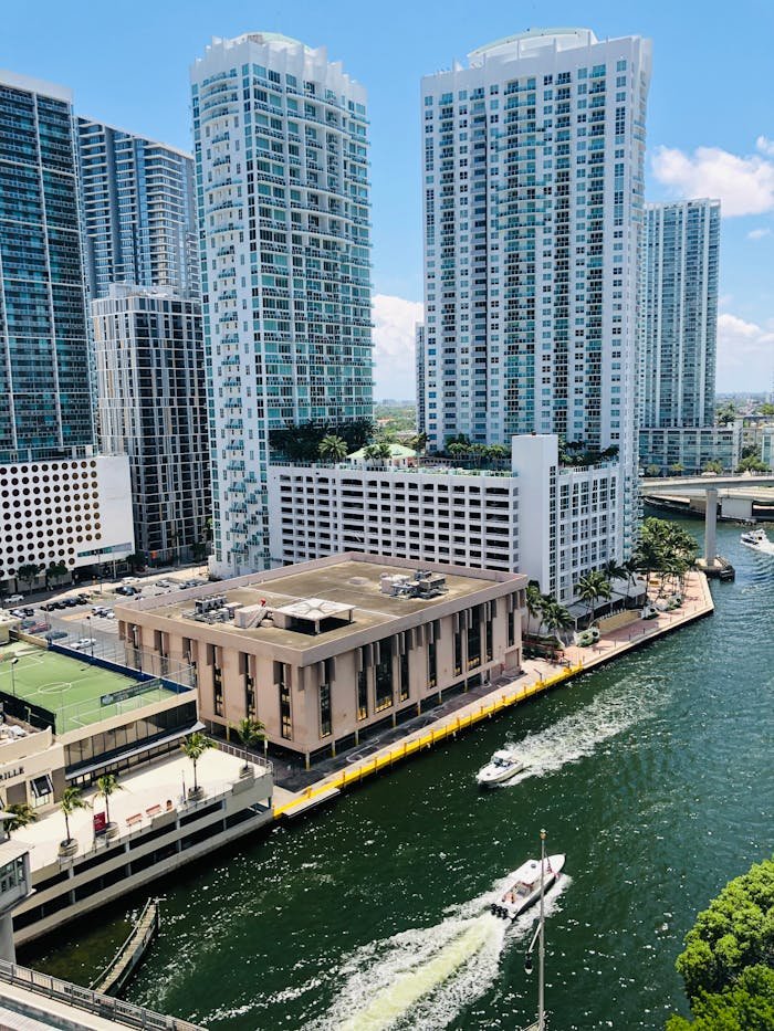Aerial view of modern skyscrapers by a lively waterfront in a vibrant city.